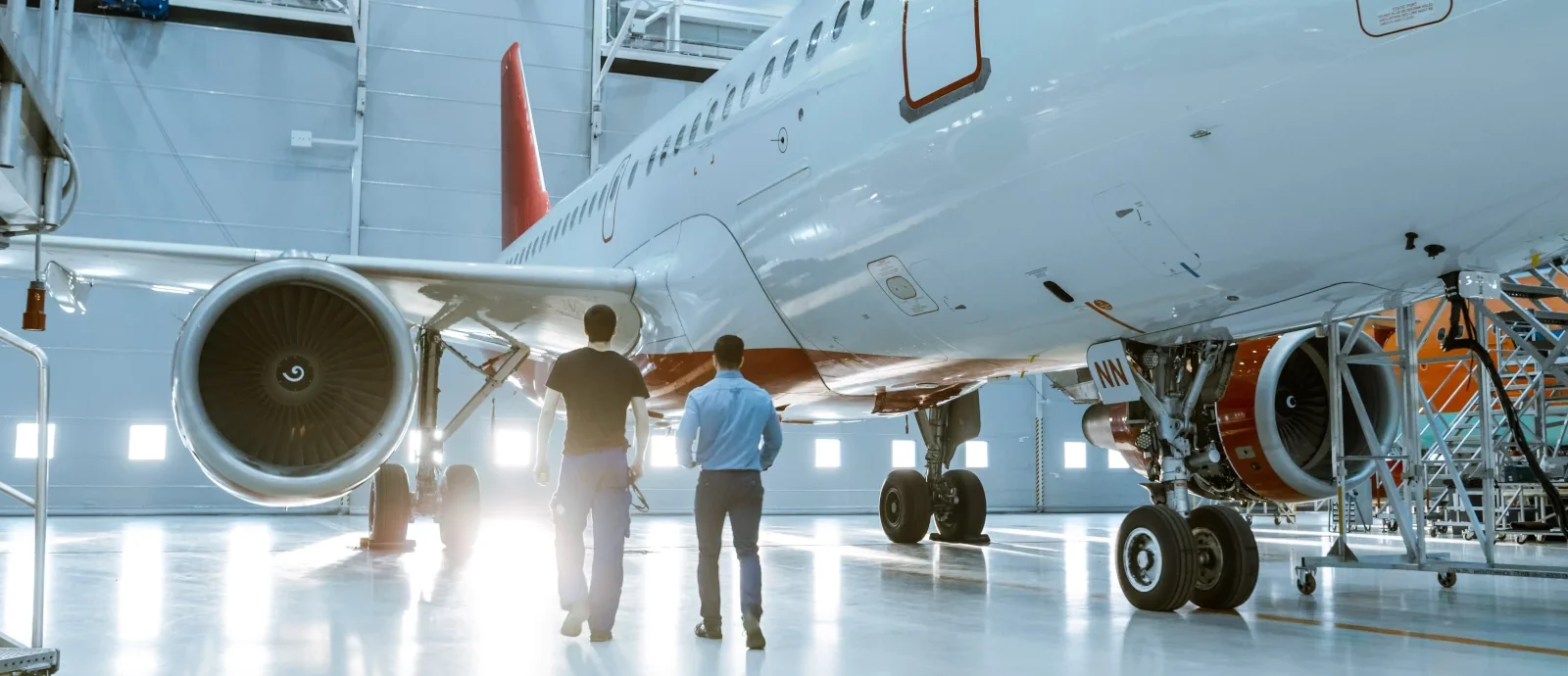 Two aircraft maintenance technicians walking toward a jet in a hangar